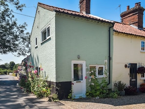 A two-story house with a green facade, a white door, and a small window.
