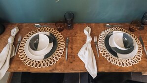 A wooden dining table set with plates, cutlery, and glasses. - The Green One On The End (Thurton)
