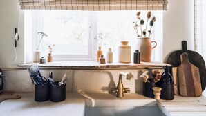 A kitchen with a window, a sink, and various kitchen utensils and containers. - The Green One On The End (Thurton)