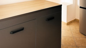Une cuisine moderne avec un plan de travail en bois, des armoires noires et un four encastré.