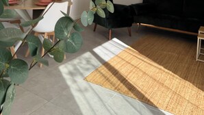 Un salon moderne avec un canapé noir, une table à manger avec des assiettes roses et une grande plante verte.