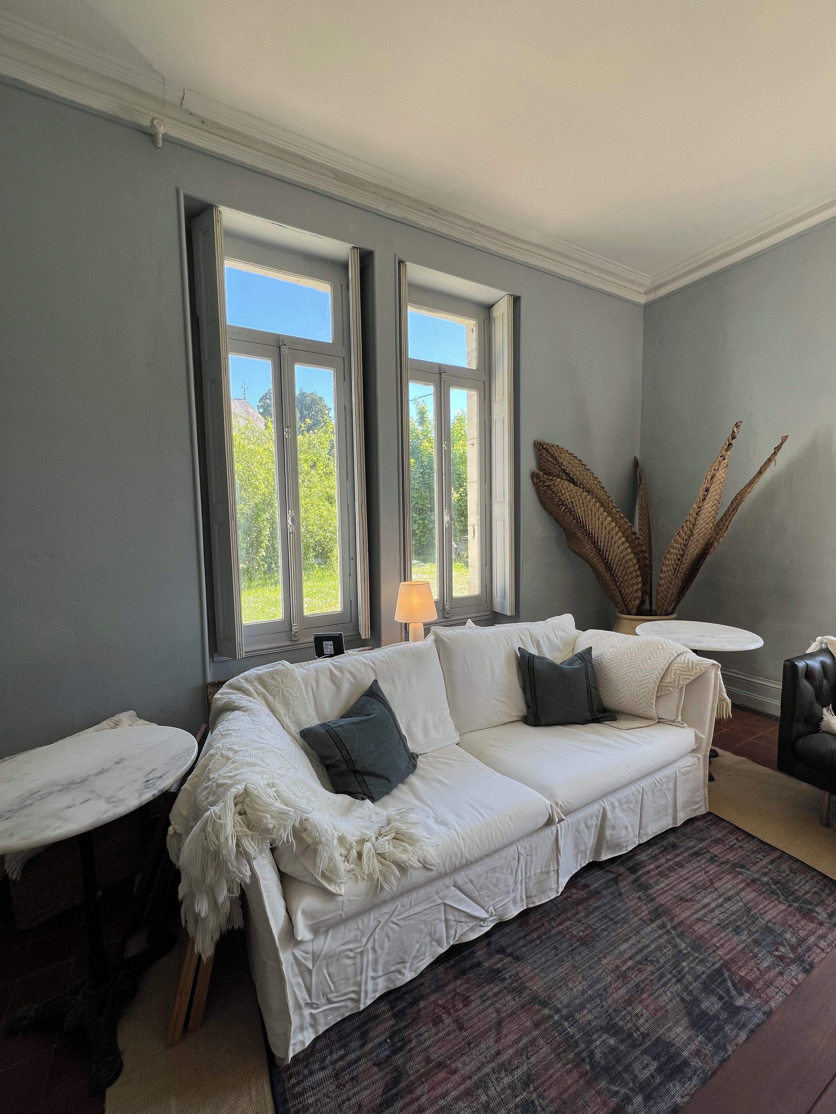 Una habitación con un sofá blanco, un tapete estampado y una lámpara.