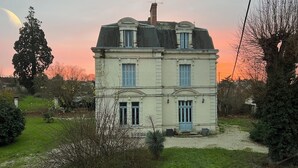 Un edificio a due piani con una facciata simmetrica, un ingresso centrale e un piccolo portico.