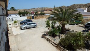 Un espace de stationnement avec plusieurs voitures, un palmier et un mur en pierre.