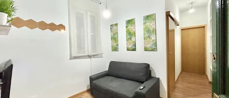 Relax in this stylish living room with a sofa, flat-screen TV, and tropical artwork.