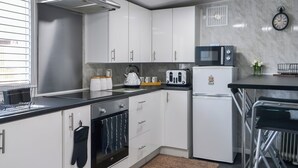 A modern kitchen with white cabinets, a stainless steel oven, a microwave, and a refrigerator.