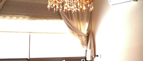 Una habitación con techo estampado, un candelabro, un sofá con cojines decorados y una pequeña mesa redonda.