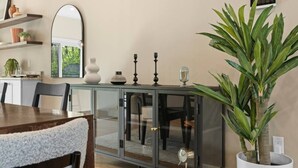 Un comedor con un aparador de vidrio, un espejo grande y una planta en maceta.