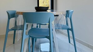 A dining area with a table and four chairs, a window with a view of trees, and a decorative mirror on the wall.