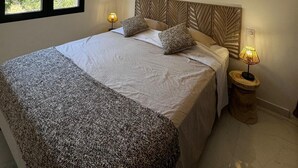 A bedroom with a large bed, two bedside lamps, a window with a view of trees, and a ceiling light fixture.