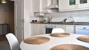 Une cuisine moderne avec des meubles blancs, un plan de travail en granit et une table à manger agrémentée de sets de table en fibres tressées.