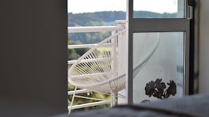 Une chaise blanche sur un balcon, avec vue sur la verdure et les collines.