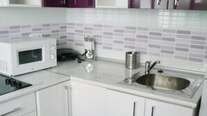 A kitchen with white cabinets, a stainless steel sink, a microwave, and a kettle. - Centro Madrid Rio - Monederos D (One bedroom apartment) (Madrid)