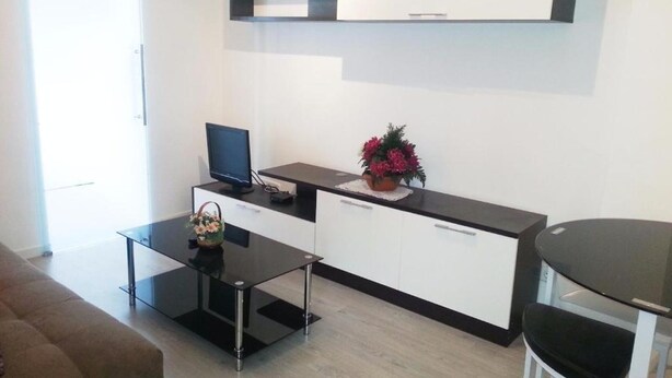 A modern kitchen with a flat-screen TV, a small dining table, and a bar stool. - Centro Madrid Rio - Monederos D (One bedroom apartment) (Madrid)