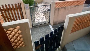 Zona residencial con entrada protegida por un muro, techo de tejas y vista de edificios a lo lejos.