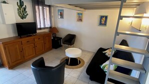 Una sala de estar moderna con un sofá, una butaca negra, un televisor y un mueble de madera.