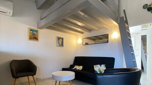 Una sala de estar con un sofá, un sillón, una mesita redonda y una maceta azul grande.