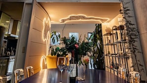 Un intérieur moderne comprenant un coin repas, un escalier et une vue sur le ciel grâce à de grandes fenêtres.