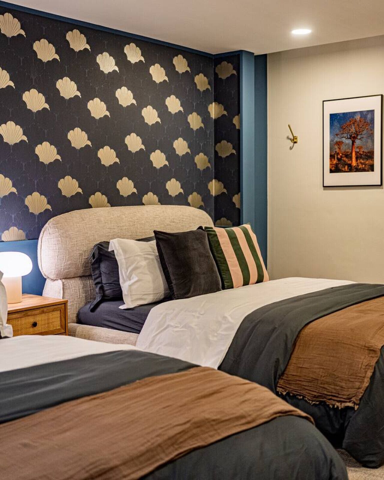 Un dormitorio con cama, mesita de noche y pared con estampado floral.