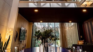 Un hall d’hôtel moderne doté d’un atrium en verre, d’un escalier et d’un comptoir d’accueil.