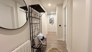 A hallway with a mirrored wall, a metal bench with cushions, a fluffy rug, and a framed picture on the wall. - Villa Aneto - Modern comfort in the heart of Benasque (Benasque)