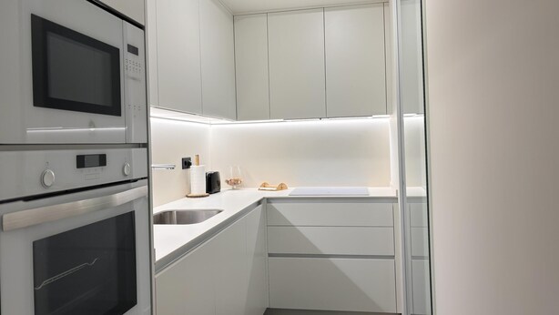 A modern kitchen with white cabinets, a built-in microwave, and a stainless steel sink. - Villa Aneto - Modern comfort in the heart of Benasque (Benasque)