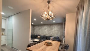 A modern dining area with a wooden table, plush chairs, and a stone wall backdrop. - Villa Aneto - Modern comfort in the heart of Benasque (Benasque)