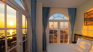 A hotel room with a bed, a view of the sunset, and a balcony with chairs. - Hoàng Hôn Hotel (Phu Quoc)