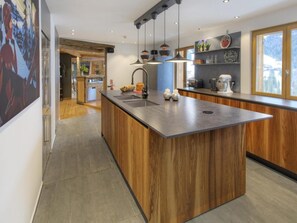 Eine moderne Küche mit einer zentralen Kochinsel, Pendelleuchten und Holzschränken.