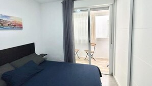A bedroom with a bed, a chair, a balcony with a view, and a painting on the wall. - Metro Avenida de América 09 (1-bedroom apartment) (Madrid)