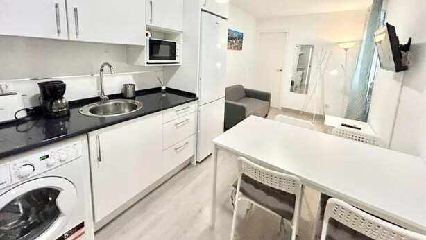A compact kitchen with white cabinets, a microwave, a coffee maker, and a washing machine. - Metro Avenida de América 09 (1-bedroom apartment) (Madrid)