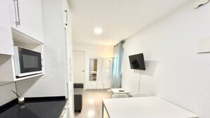 A modern kitchen with a microwave, a sink, and a dining area with a white table and chairs. - Metro Avenida de América 09 (1-bedroom apartment) (Madrid)