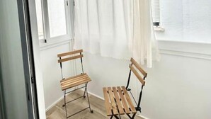 A room with two wooden chairs, a window with white curtains, and a light-colored floor. - Metro Avenida de América 09 (1-bedroom apartment) (Madrid)