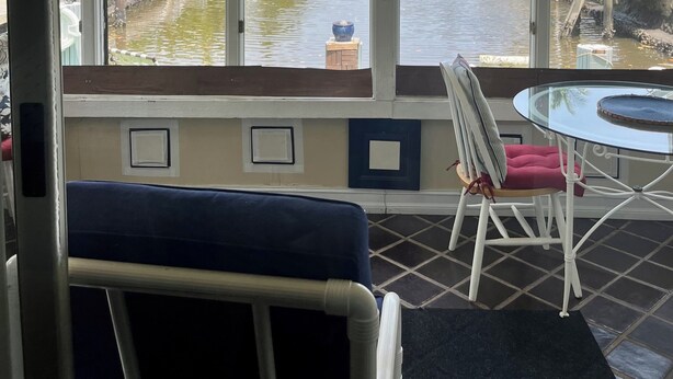 Une chambre avec vue sur un canal, un ventilateur de plafond, une table avec une chaise et une fenêtre avec des stores.