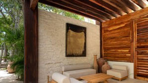 An outdoor patio with a sofa, two chairs, and a coffee table. - NHOA 312B Lux 1BR Condo Top Jungle View Aldea Zama (Tulum)