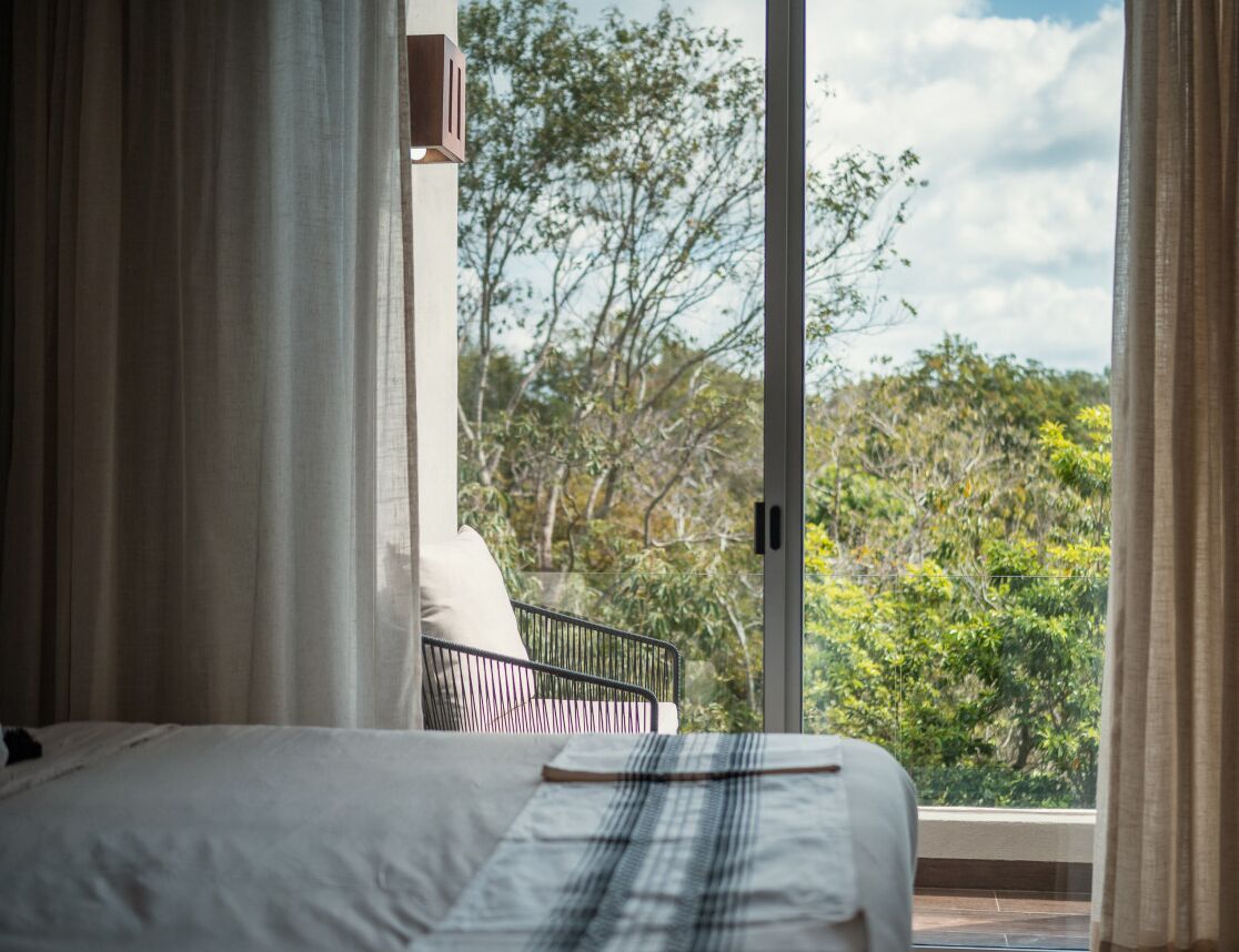 A bedroom with a bed, a window, and a view of trees.
