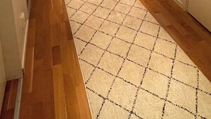 A hallway with wooden flooring, a patterned rug, a small shelf with decorative items, a staircase, and a door. - Room-bed & Breakfast in Stockholm (Bromma)