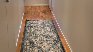 A hallway with wooden flooring, a patterned rug, a window with a view, and a painting on the wall. - Room-bed & Breakfast in Stockholm (Bromma)
