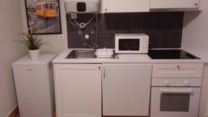 A compact kitchen with a microwave, sink, and small refrigerator.