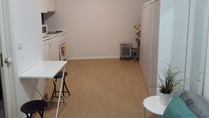 A compact kitchen with a white countertop, a small stool, and a radiator.