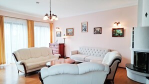 En stue med en hvid sofa, to lænestole, et træsofabord og en pejs.