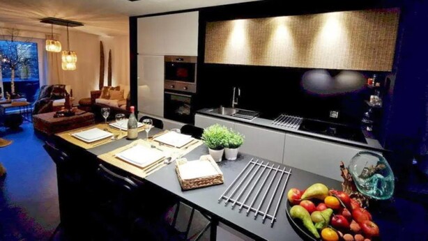 A modern kitchen with a central island, built-in oven, and a large window overlooking the city. - Cottage in Houyet Near Lesse River Trails (Houyet)