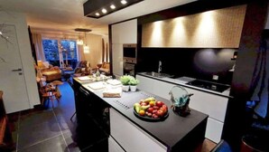A modern kitchen with a central island, a dining area with a sofa and chairs, and a view of the outdoors. - Cottage in Houyet Near Lesse River Trails (Houyet)