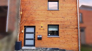 A modern building with horizontal wooden siding, a black door, and two windows. - Cottage in Houyet Near Lesse River Trails (Houyet)