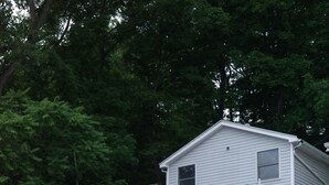 A two-story house with a dock and kayaks. - Charming Vintage Lakefront Cottage on Seneca Lake (Penn Yan)
