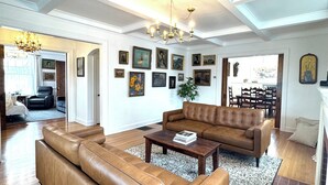 Un salon spacieux avec un grand canapé en cuir marron, une table basse en bois et un lustre.