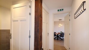 A hallway with white doors, a wooden column, and a dining area in the background. - Apartment in Workum Near Ijsselmeer Beach (Workum)