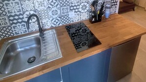 A kitchen with a stainless steel sink, a black cutting board, and a utensil holder with knives and spoons.
