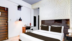 Une chambre d’hôtel moderne dotée d’un grand lit, d’un bureau, d’une chaise, d’une table de chevet et d’un mur orné d’un motif circulaire.