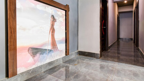 Un couloir avec une grande œuvre d’art encadrée, un sol en marbre et une porte sur la droite.